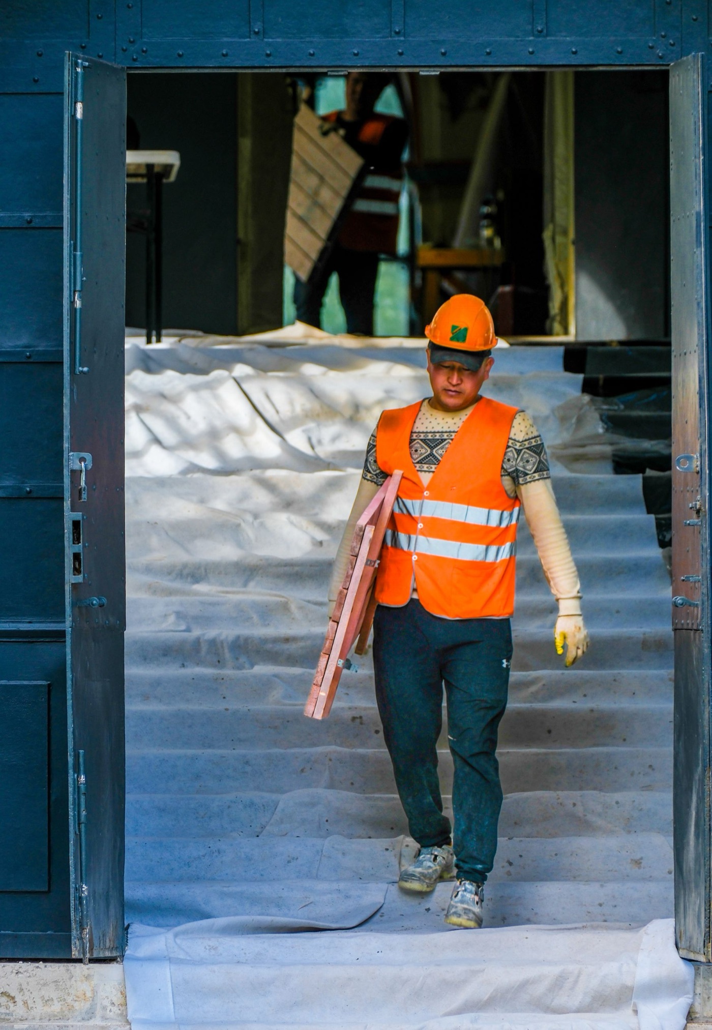A contractor carrying tools through an active renovation site