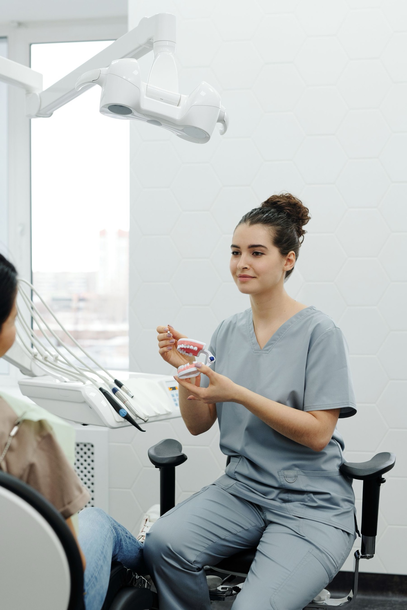 A dental professional explaining oral care to a patient using a model