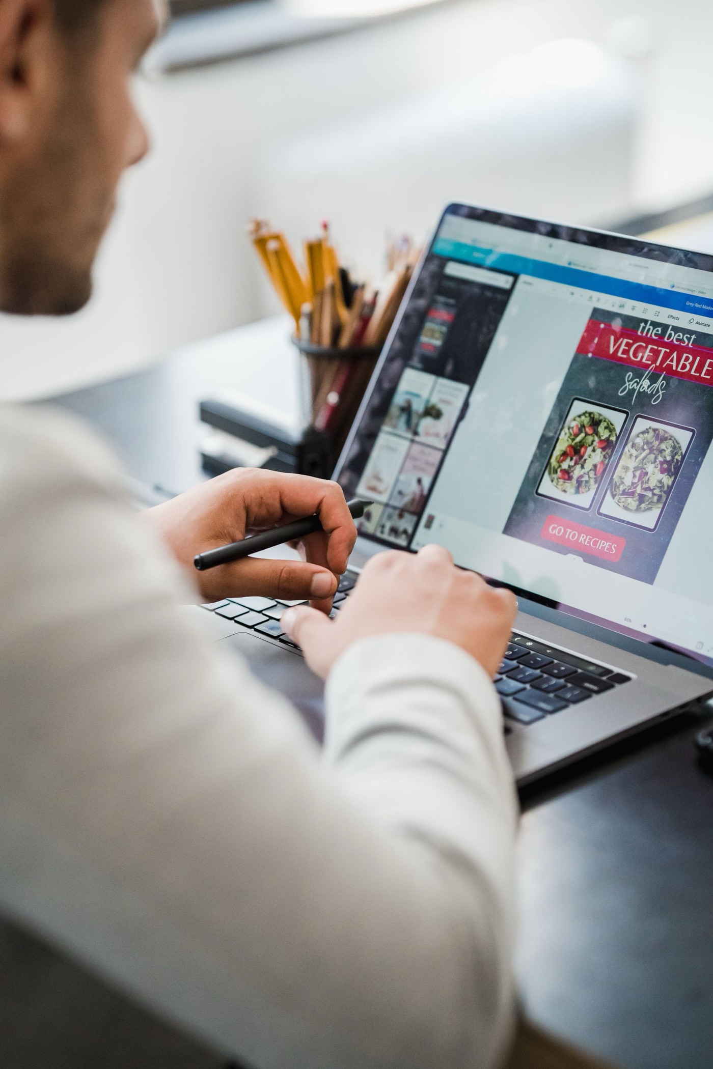A graphic designer refining visual work on a laptop in a bright studio